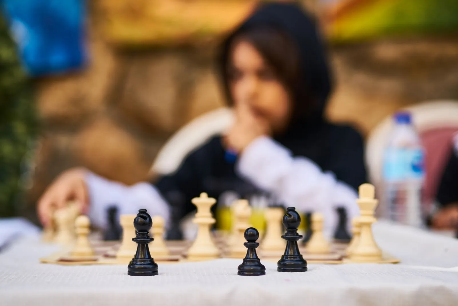 Young player focuses on chess game outdoors, highlighting strategy and determination.